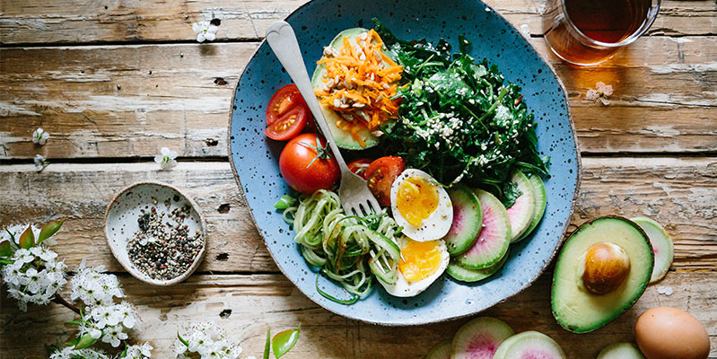 Ein leckerer Salat mit Tomaten, Avocado und Ei ist eine gute Alternative zu ungesunden Snacks